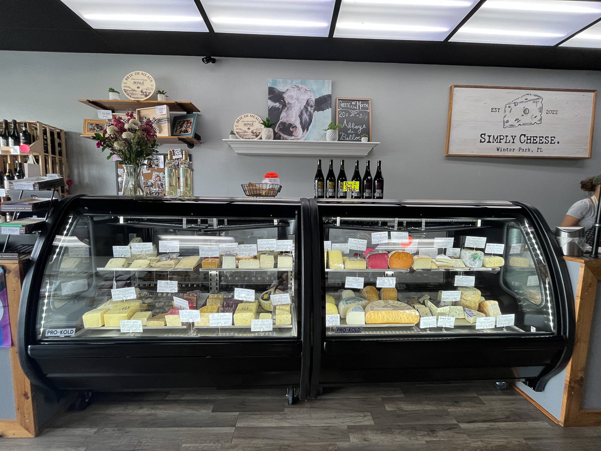 glass case with various types of cheese